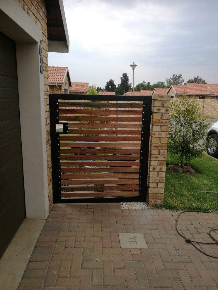 Steel pedestrian gate with hardwood slats and gaps between the timber
